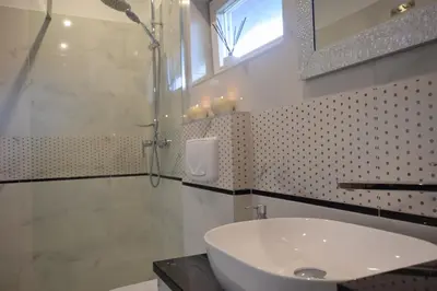 a bathroom with a sink and a shower and a mirror at Domek Anielski in Zator