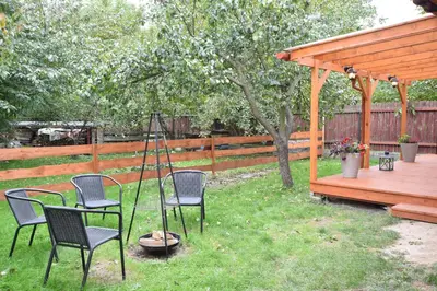 a yard with chairs and a table and a wooden pergola at Domek Anielski in Zator