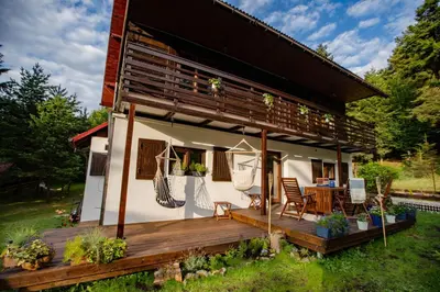 a house with a wooden deck in the yard at Chata Pod Lasem in Poręba