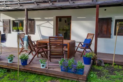 a deck with chairs and a table and some plants at Chata Pod Lasem in Poręba