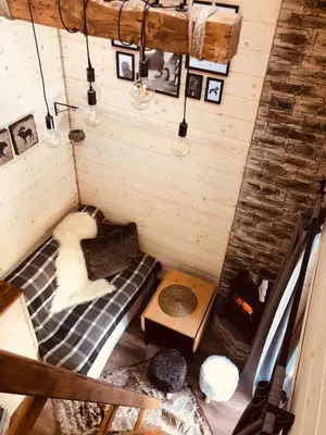 a dog laying on a bed in a tiny house at Chata Pod Lasem in Poręba