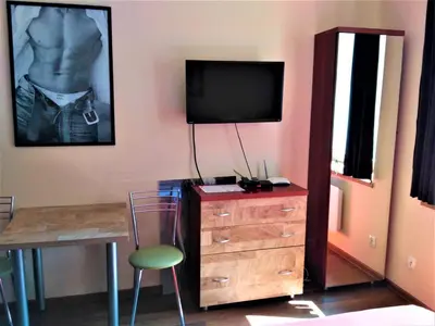 a room with a dresser with a tv and a chair at Akt Studio Apartment City Centre in Kraków
