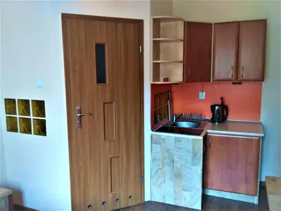 a kitchen with a wooden door and a sink at Akt Studio Apartment City Centre in Kraków