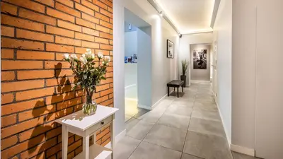 a hallway with a brick wall and a vase of flowers on a table at Flaminio Smart Sleep in Kraków