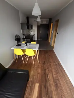 a living room with a table and yellow chairs at Apartament Cyprys 2 in Oświęcim