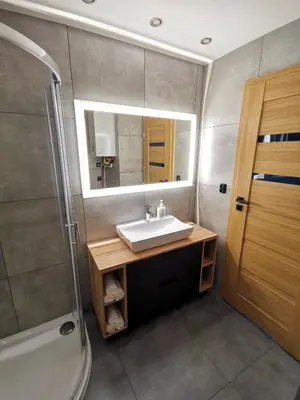 a bathroom with a sink and a shower and a mirror at Apartament Cyprys 2 in Oświęcim