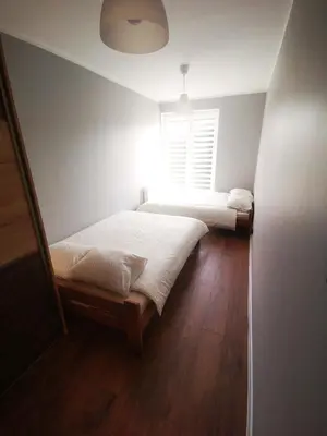 two beds in a small room with a window at Apartment Cyprys 1 in Oświęcim