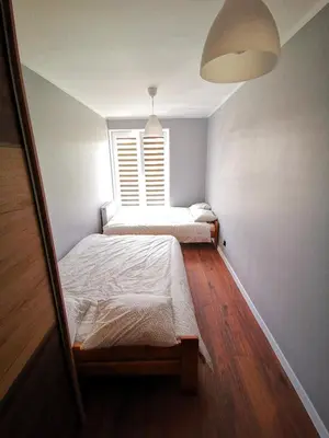 two beds in a small room with a window at Apartment Cyprys 1 in Oświęcim