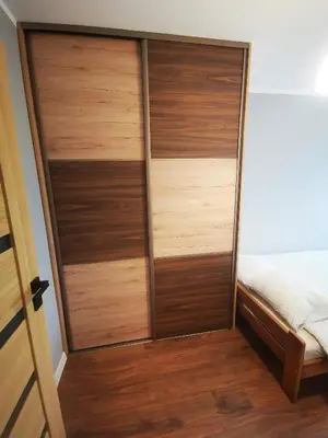 a closet with wooden doors next to a bed at Apartment Cyprys 1 in Oświęcim
