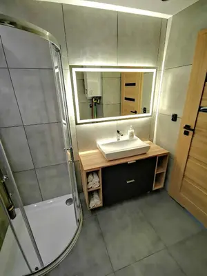 a bathroom with a sink and a shower and a mirror at Apartment Cyprys 1 in Oświęcim