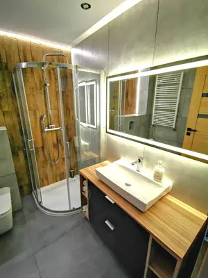 a bathroom with a sink and a shower with a mirror at Apartment Cyprys 1 in Oświęcim