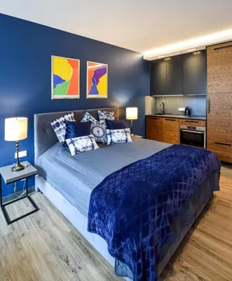 a blue bedroom with a bed and a kitchen at In City Apartments Rajska 3 in Kraków