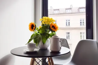 a table with a vase of sunflowers and two cups at In City Apartments Rajska 3 in Kraków