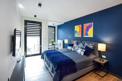 a bedroom with blue walls and a bed and a television at In City Apartments Rajska 3 in Kraków