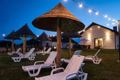a group of chaise lounges and umbrellas in a yard at Słoneczne Wzgórze Zator in Zator