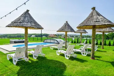 a group of chairs and umbrellas next to a pool at Słoneczne Wzgórze Zator in Zator