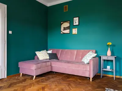 a living room with a pink couch and a green wall at Green view apartment / Kochanowskiego in Kraków