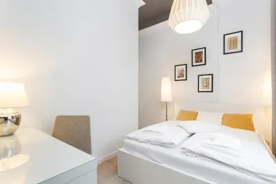 a white bedroom with a bed and a desk at Apartment Krakow Arianska by Renters Prestige in Kraków