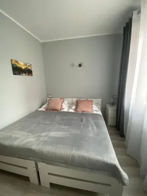 a white bedroom with a bed with pink pillows at Pokoje u Jasia i Małgosi in Skawa
