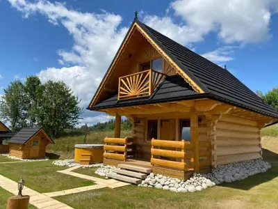 a small log cabin with a black roof at Domki Gorce Klikuszowa Sauna Jacuzzi in Klikuszowa