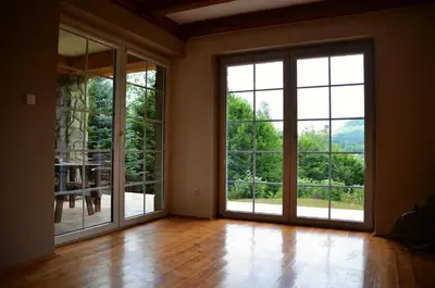 an empty room with large windows and wooden floors at Dom w Beskidach in Stryszawa