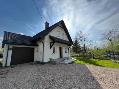 a white house with a garage on a gravel driveway at Dom nad Skawą - Zator 5km in Grodzisko