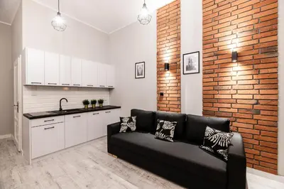 a living room with a black couch and a brick wall at Dietla 32 Residence - ideal location in the heart of Krakow, between Main Square and Kazimierz District in Kraków