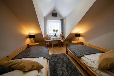 two beds in a room with a table and a window at Gościniec pod Lilijką in Podzamcze