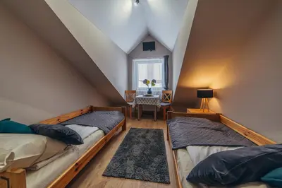 two beds in a room with a table and a window at Gościniec pod Lilijką in Podzamcze
