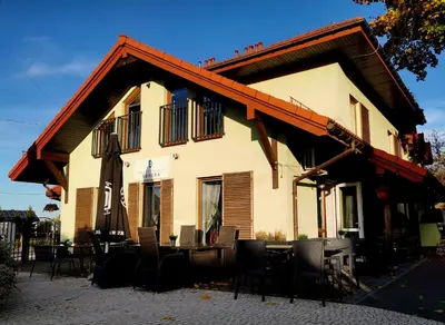 a building with a table and chairs in front of it at Gościniec pod Lilijką in Podzamcze