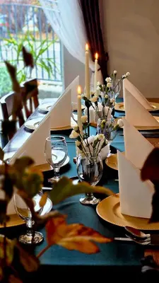 a table with a blue table cloth with candles and flowers at Gościniec pod Lilijką in Podzamcze