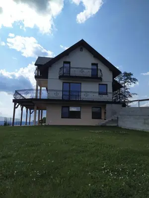 a house with a deck on top of a grass field at Cicha Chata Kudłacze in Pcim