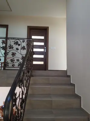 a staircase with a wrought iron railing and a door at Cicha Chata Kudłacze in Pcim