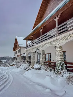 a building with snow on the ground in front of it at Hotel Łokietek in Czajowice
