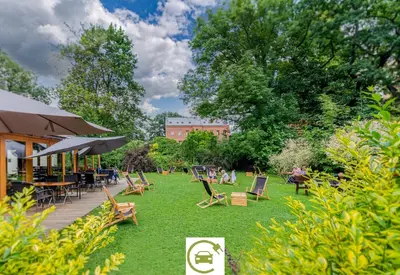 a park with chairs and tables on the grass at Hotel Yarden by Artery Hotels in Kraków