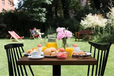 a table with breakfast food and orange juice and flowers at Hotel Yarden by Artery Hotels in Kraków
