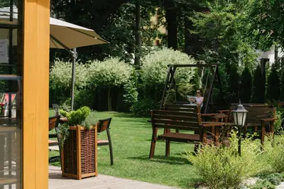 a person sitting on a swing in a garden at Hotel Yarden by Artery Hotels in Kraków