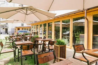 an outdoor restaurant with tables and chairs and umbrellas at Hotel Yarden by Artery Hotels in Kraków