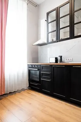 a kitchen with black cabinets and a wooden floor at HOUSEHOST Apartment: Łazarza II street in Kraków