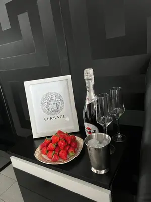 a table with a plate of strawberries and a bottle of wine at Apartament Lema Versace in Kraków