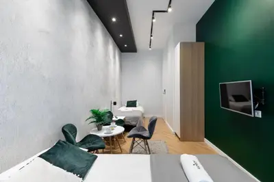 a bedroom with a green accent wall and two beds and chairs at Rainbow Apartments 3 in Kraków