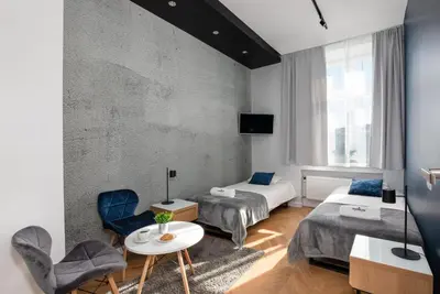 a hotel room with two beds and a table and chairs at Rainbow Apartments 3 in Kraków