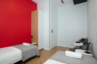 a room with two beds and a red wall at Rainbow Apartments 3 in Kraków