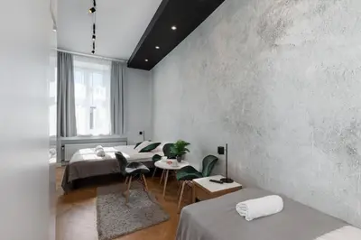 a bedroom with two beds and a concrete wall at Rainbow Apartments 3 in Kraków