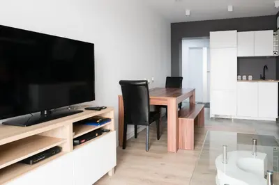 a living room with a dining room table with a flat screen tv at Republiki Korczakowskiej Ferienwohnung in Kraków