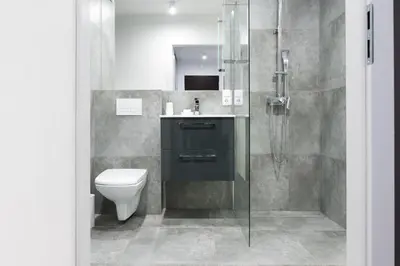 a bathroom with a toilet and a glass shower at Republiki Korczakowskiej Ferienwohnung in Kraków