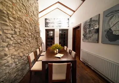 a dining room with a table and a stone wall at Ojców Bazar Lwowski in Ojców