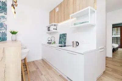 a white kitchen with a sink and a counter at Apartament 3d GO by Noclegi Renters in Kraków