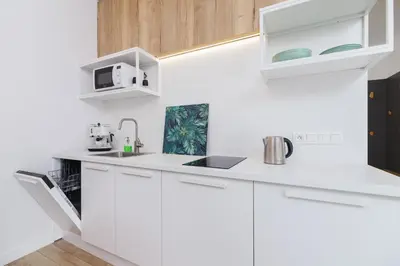 a white kitchen with white cabinets and a microwave at Apartament 3d GO by Noclegi Renters in Kraków