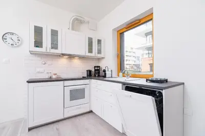a kitchen with white cabinets and a window at Apartments Cracow Rakowicka by Noclegi Renters in Kraków